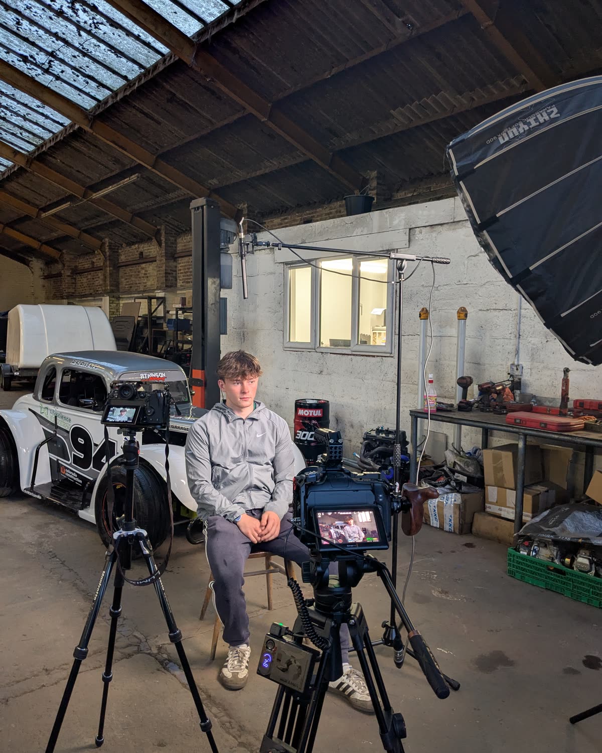 Behind the scenes filming an interview in a garage beside a racing car